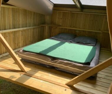 Intérieur de la cabane en bois avec lit double et verrière au Cop'campétoiles