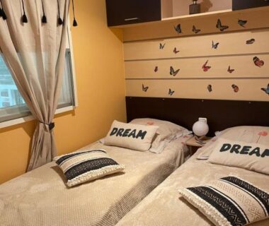 Chambre avec deux lits simples rideaux et papillons muraux dans le Coquet mobilehome 8 places