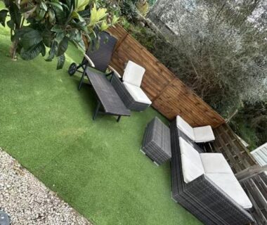 Coin salon extérieur sur gazon synthétique avec fauteuils et table dans le Coquet mobilehome 8 places