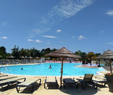 Piscine extérieure bordée de transats et parasols au camping Cordon LMP