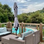 Terrasse en bois avec salon de jardin et piscine en contrebas du Cosy mobil-home wifi clim