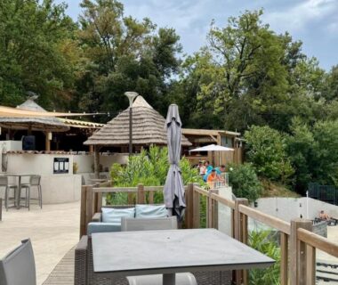 Terrasse au bord de la piscine avec tables parasols et coin salon du Cosy mobil-home wifi clim