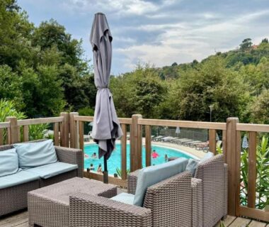 Terrasse en bois avec salon de jardin et piscine en contrebas du Cosy mobil-home wifi clim