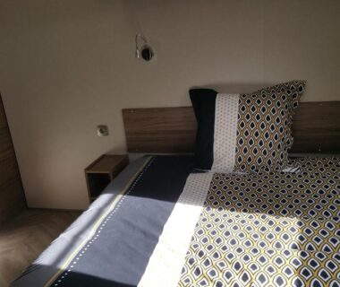 Chambre avec lit double et tête de lit en bois dans le mobilhome Côte d’Émeraude Mobilhome
