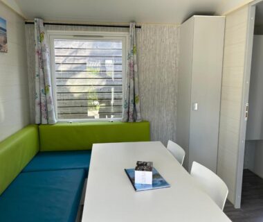 Séjour avec banquette verte table et fenêtre dans le Cottage Essentiel 30m2