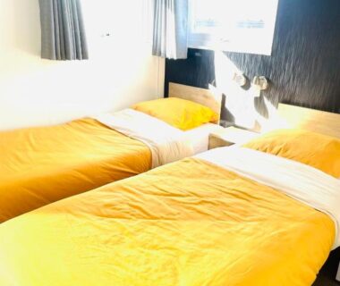 Chambre avec deux lits simples et couettes jaunes au Cottage Premium