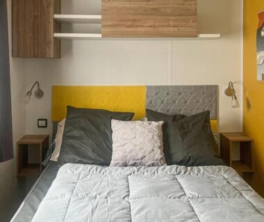 Chambre avec lit coussins et tables de chevet dans le Cozy Stacaravan In Saint-Julien-En-Born