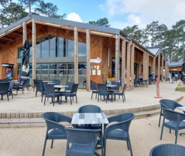 Terrasse extérieure avec tables et chaises devant le bâtiment principal du Cozy Stacaravan In Saint-Julien-En-Born