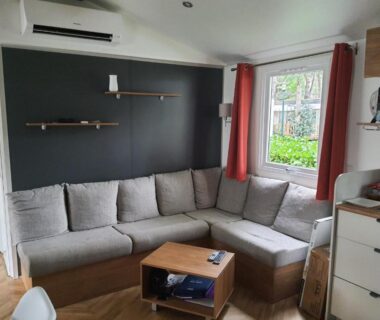 Coin salon avec canapé d'angle et kitchenette dans le mobil-home Détente et Lac