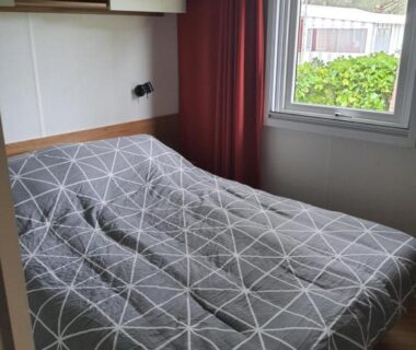 Chambre avec lit double et fenêtre donnant sur jardin au camping Détente et Lac