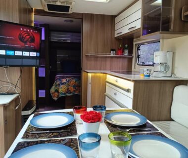 Intérieur coin repas avec table dressée et kitchenette dans le Dodo mobile