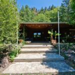 Escalier menant à une terrasse couverte entourée d'arbres du Domaine La Faix Gite La Cigogne