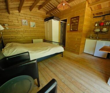 Intérieur en bois avec lit et kitchenette dans le Gite La Cigogne au Domaine La Faix