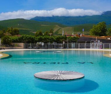 Piscine extérieure avec plateforme flottante et collines en arrière-plan au Domaine La Pietra