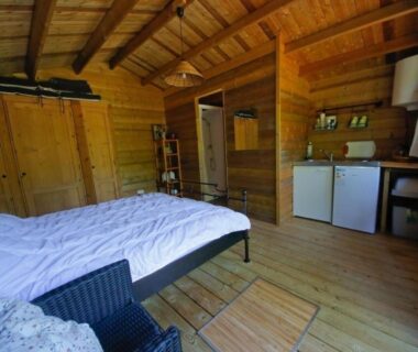 Intérieur en bois avec lit et kitchenette du Gite le Verger