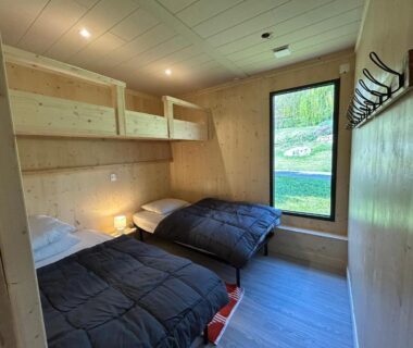 Chambre en bois avec lits superposés et fenêtre sur le jardin au Domaine Napoléon