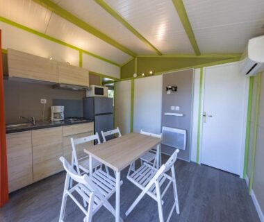 Intérieur séjour avec kitchenette et table au Domaine Plein Sud