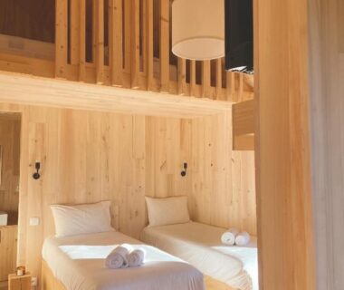 Intérieur de chambre en bois avec lits jumeaux mezzanine et serviettes au Domaine St-Amand