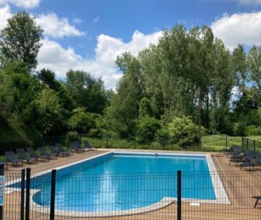 Piscine extérieure entourée d'arbres et terrasse en bois au Domaine de Guillaume
