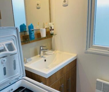 Salle d'eau avec lave-linge et lavabo dans le Domaine de Kerlann