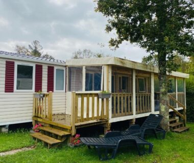 Mobil-home avec terrasse couverte et transats sur pelouse au Domaine de Kerlann