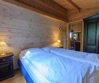 Chambre en bois avec deux lits chevets et armoire au Domaine de Maples