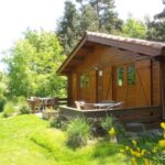 Chalet en bois sur pelouse avec terrasse et mobilier de jardin au Domaine de Maples