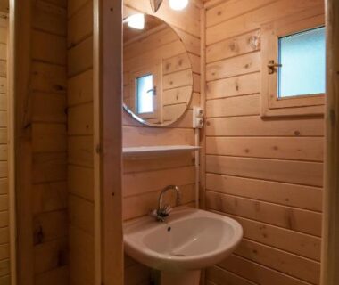 Salle de bains en bois avec lavabo et miroir au Domaine de Maples