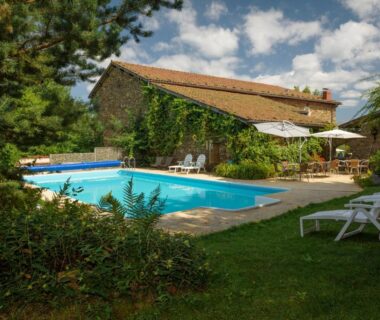 Piscine extérieure bordée de pelouse devant maison en pierre au Domaine de Maples