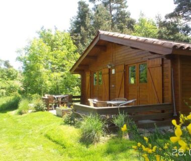 Chalet en bois sur pelouse avec terrasse et mobilier de jardin au Domaine de Maples