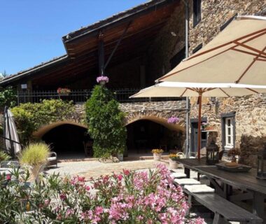 Cour en pierre avec parasols et tables au Domaine de Maples