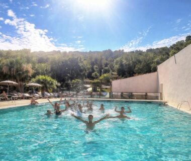 Piscine extérieure avec baigneurs dans un cadre boisé au Domaine de Miremer