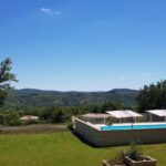 Piscine extérieure et pelouse avec vue sur les collines au Domaine de la Chêneraie