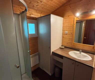 Salle de bain en bois avec douche et lavabo au Domaine de la Chêneraie