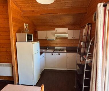 Cuisine en bois avec frigo et échelle dans un chalet du Domaine de la Chêneraie