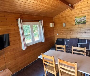Intérieur de chalet en bois avec table et canapés au Domaine de la Chêneraie