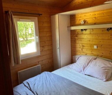 Chambre en bois avec lit et fenêtre dans le Domaine de la Chêneraie