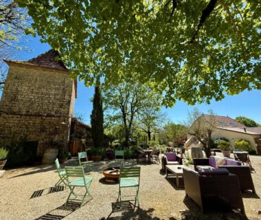 Cour ombragée avec fauteuils et chaises sous arbres du Domaine de la Faurie