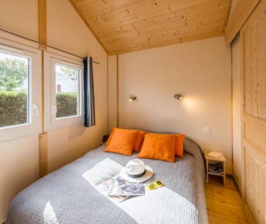 Chambre en bois avec lit double et fenêtres dans le Domaine de la Forge