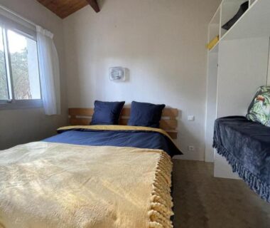 Chambre avec lit couverture jaune et poutres apparentes au Domaine de la Presqu'île