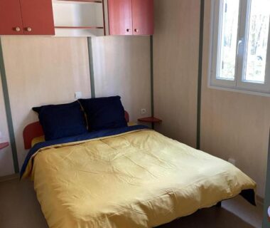 Chambre avec lit double et couette jaune dans le mobil-home du Domaine de la Presqu'île