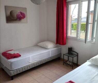 Chambre avec deux lits simples et fenêtre ouverte au Domaine des Garrigues