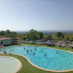 Piscine extérieure avec baigneurs et pelouse au Domaine des Garrigues