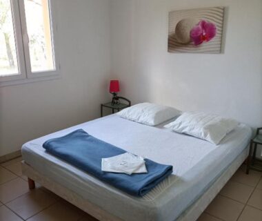 Chambre avec lit double et fenêtre au Domaine des Garrigues