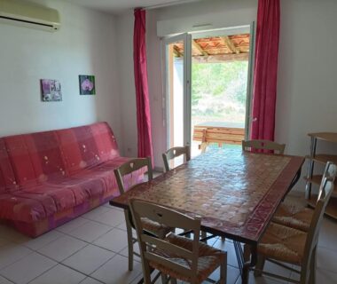 Séjour avec table et canapé donnant sur terrasse et paysage dans le Domaine des Garrigues
