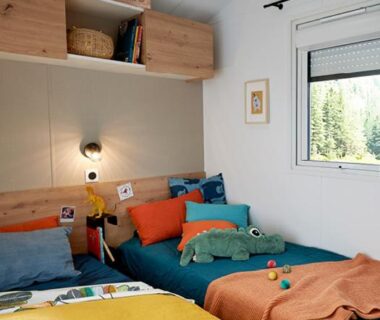 Intérieur chambre avec deux lits colorés et peluche au Domaine du Blanc Pignon