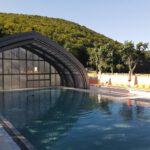 Piscine extérieure avec abri transparent et transats au Domaine du Lac Chambon
