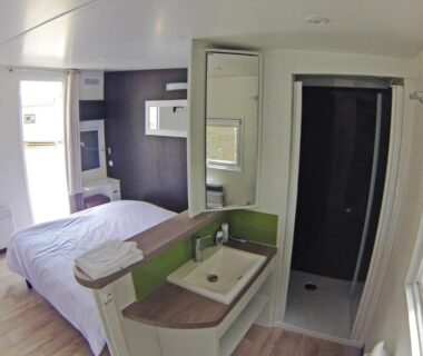 Intérieur mobil-home avec lit lavabo et douche au Domaine du Lac Chambon