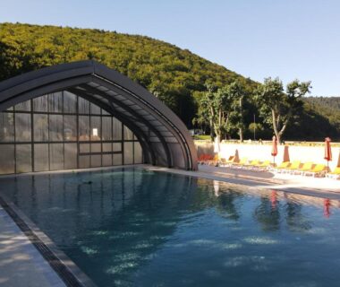 Piscine extérieure avec abri transparent et transats au Domaine du Lac Chambon
