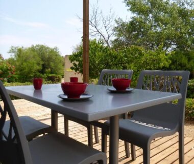 Terrasse en bois avec table, chaises et tasses rouges au Domaine du Lac Chambon